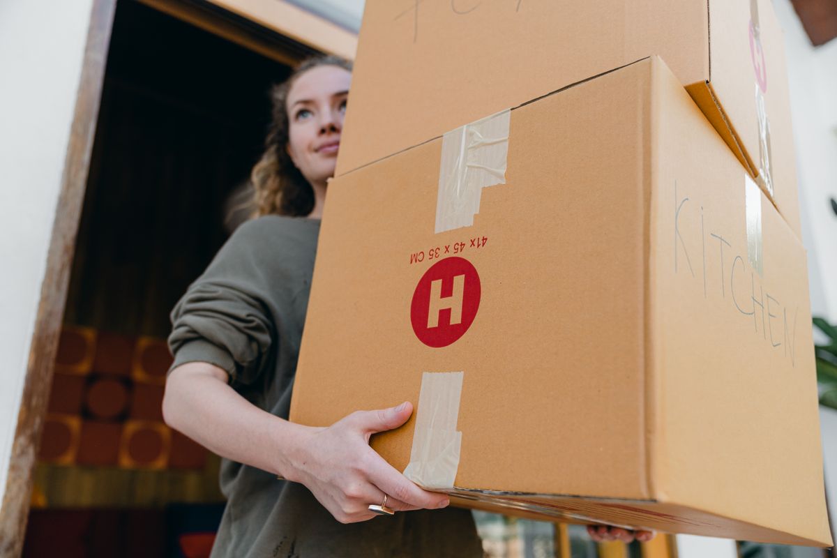 A mover carrying a large moving box out of a truck