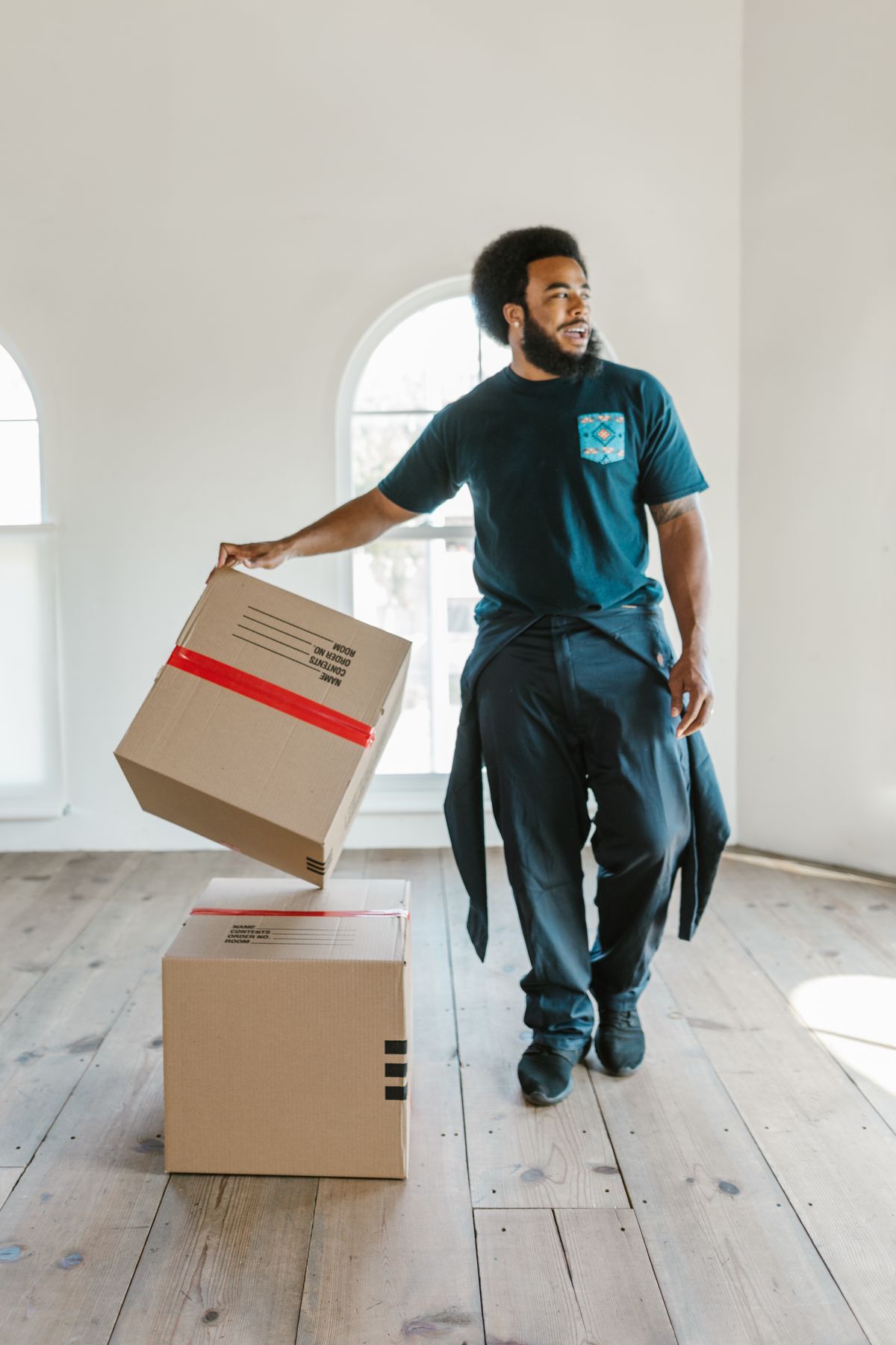 A mover carrying a moving box through a bright home