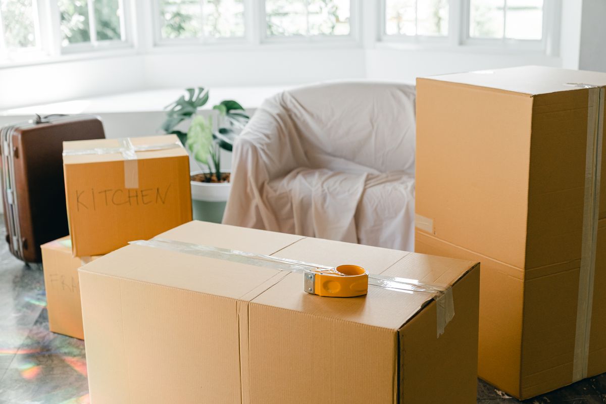Packed moving boxes and a wrapped sofa in a living room