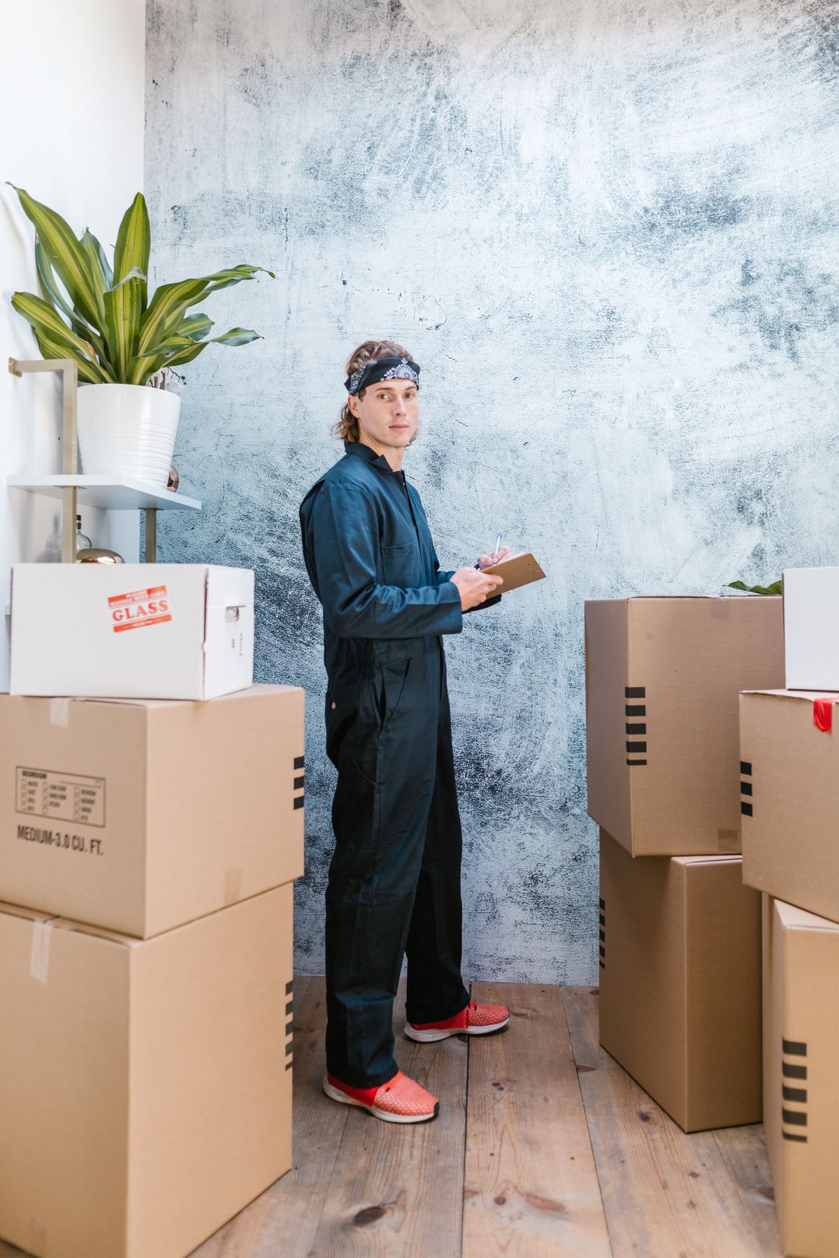 A woman with a clipboard standing among packed moving boxes