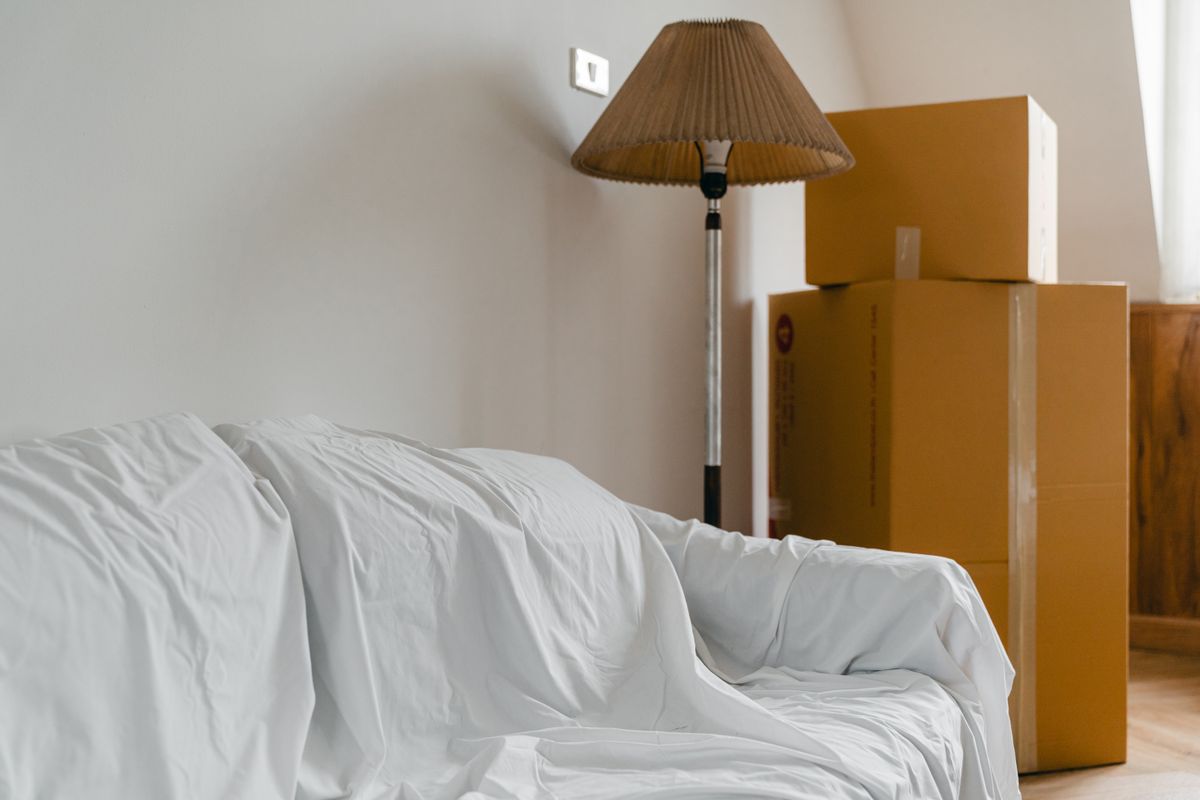 A sofa covered with a protective sheet next to packed boxes