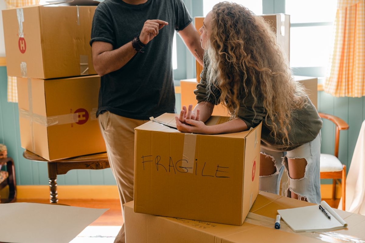 A couple discussing a box marked fragile during packing
