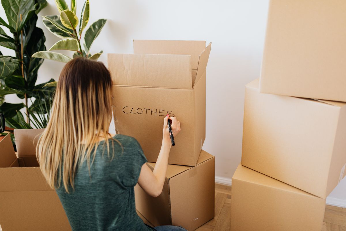 A woman writing a room name on a moving box