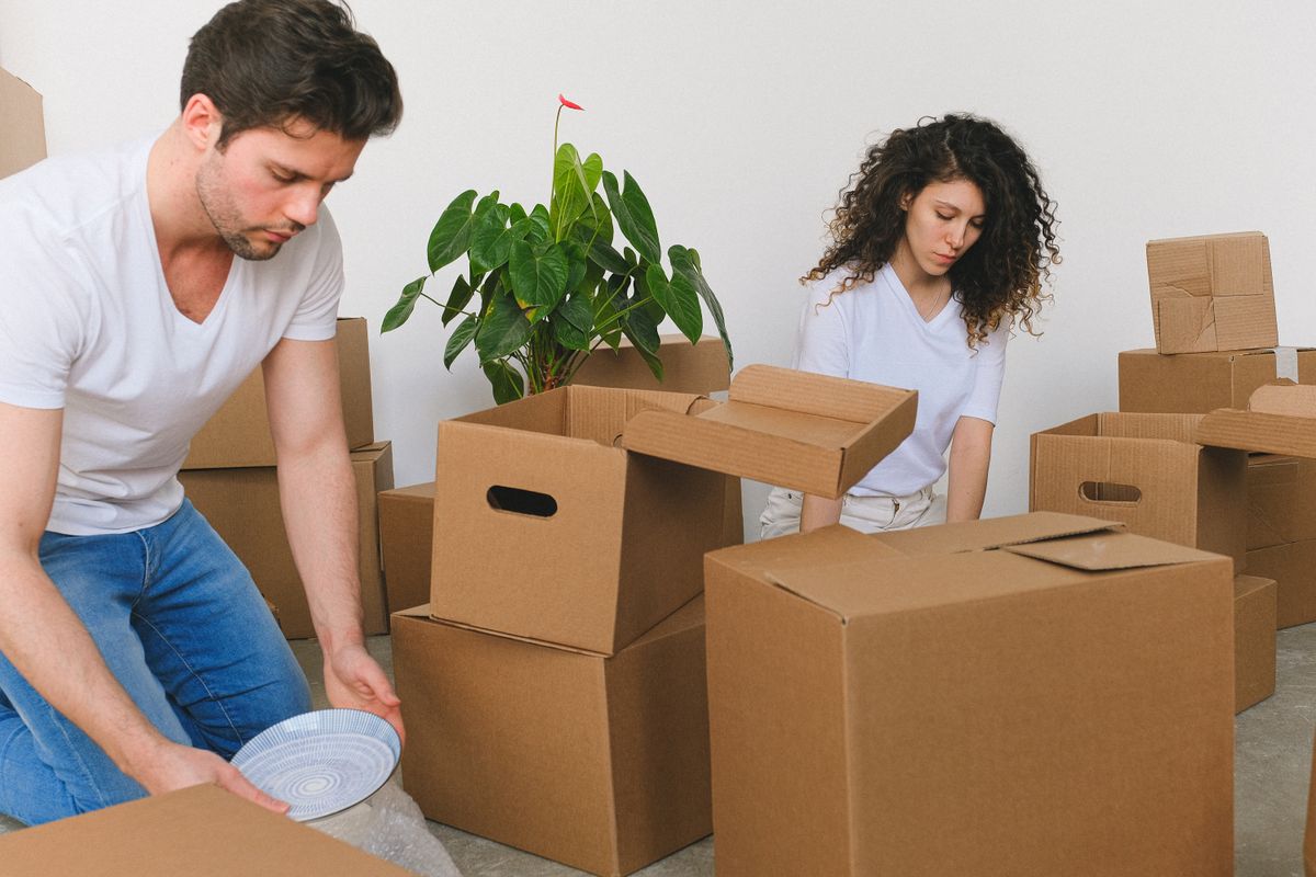 A couple packing dishes into moving boxes