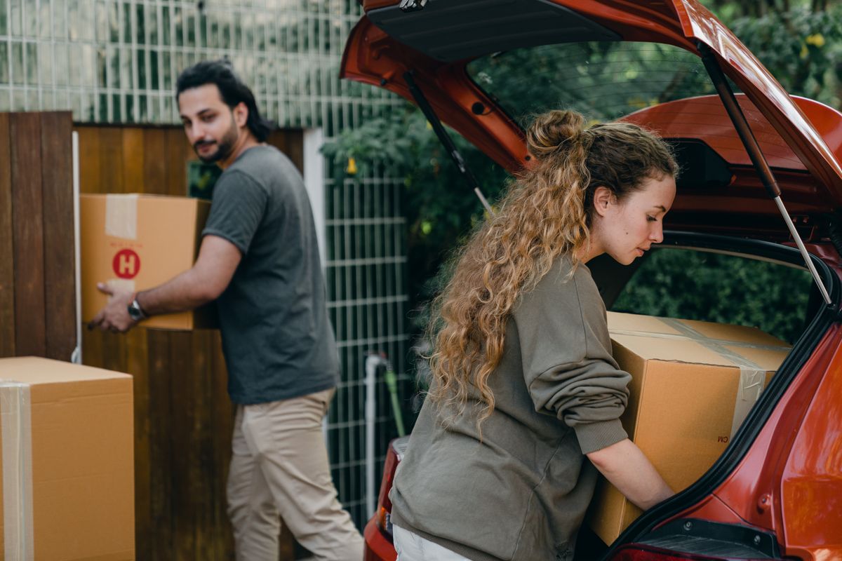 A couple loading moving boxes into a vehicle with help